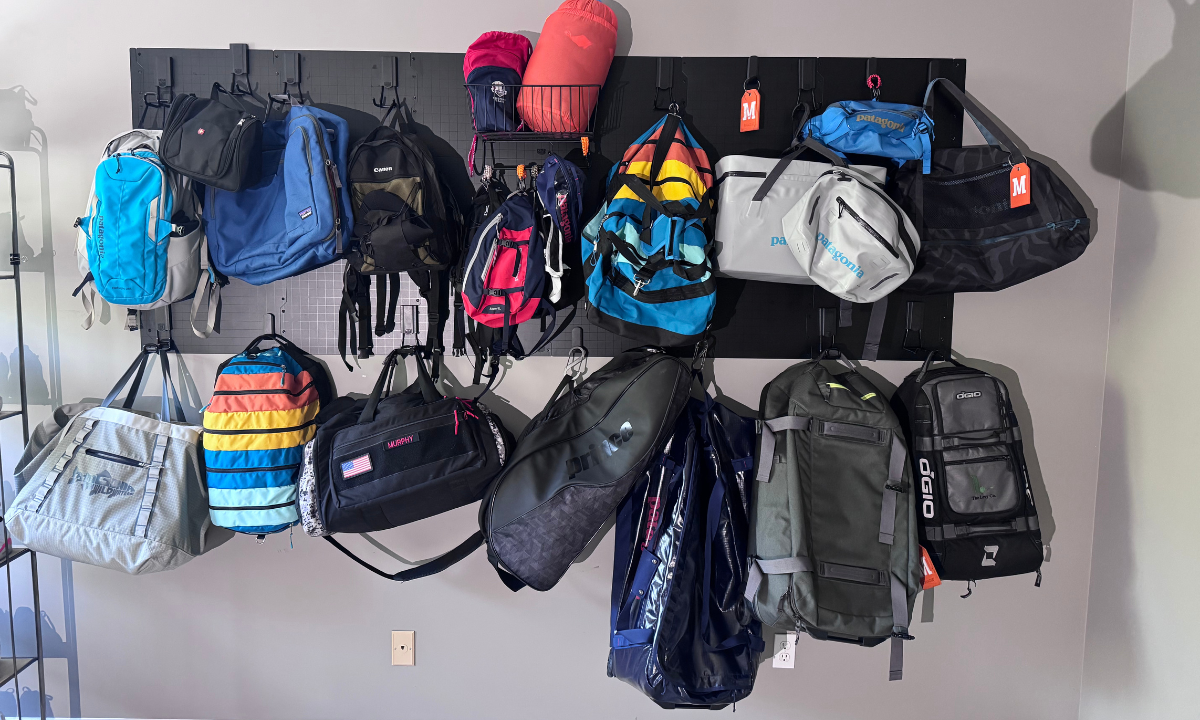 Backpacks and duffel bags organized on a Gator Steel Wall Panel with magnetic hooks.