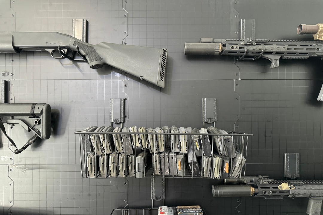 Gator magnetic basket holds rifle magazines between two rifles mounted on a steel wall panel.
