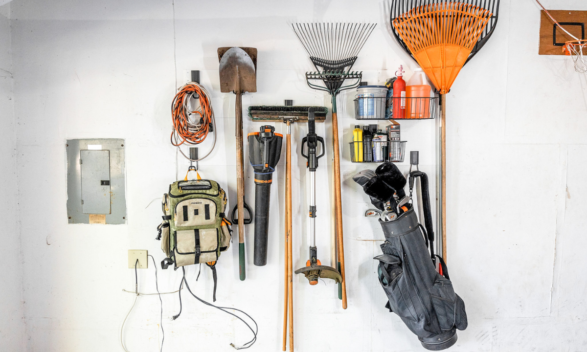 Gator magnetic hooks organize leaf blowers, rakes, shovel and a bag on steel wall rails.