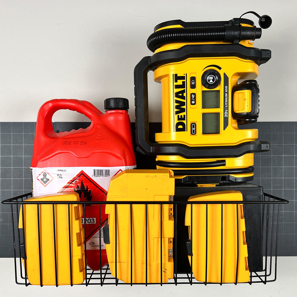 A black magnetic storage basket from Gator Magnetics holds a red 5L gasoline container and three yellow DEWALT battery chargers on a flat steel wall panel, demonstrating practical home backpack storage organization.