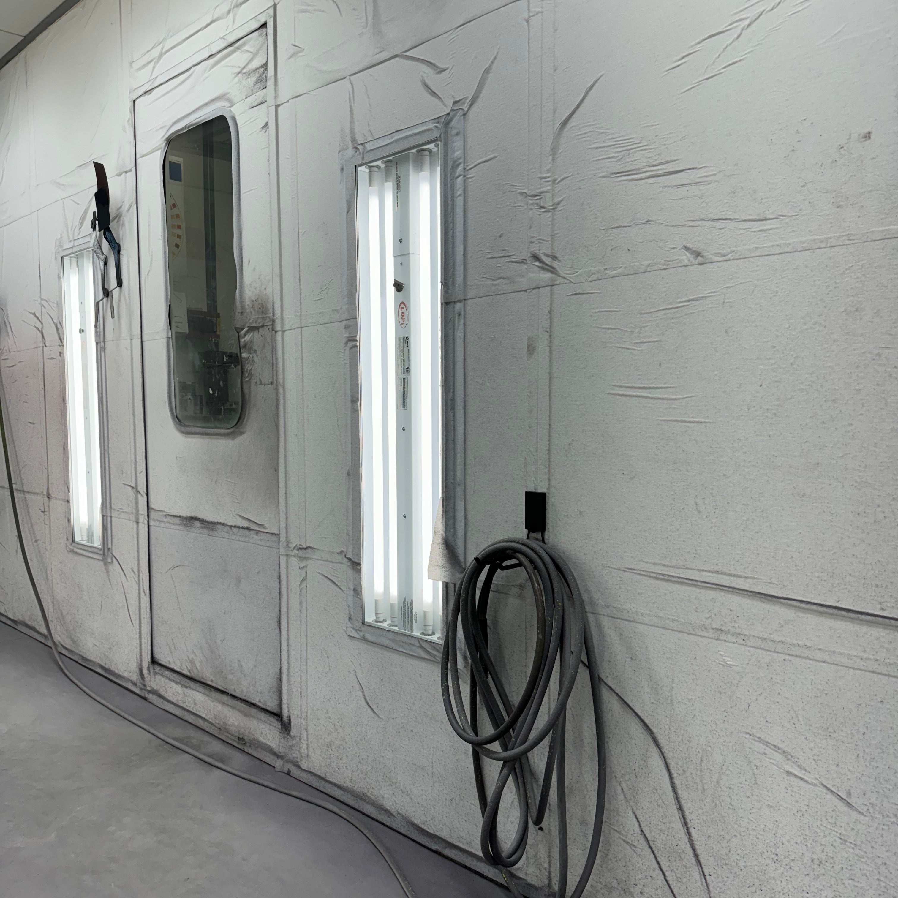 Gator Magnetics 4.5 inch closed magnetic hook holding industrial air hose on steel wall in paint shop, heavy-duty magnetic hook for hoses, garage and workshop hose hanger magnetic hook, Gator Magnetics hook for air compressor hose storage, magnetic hook for automotive shop organization.