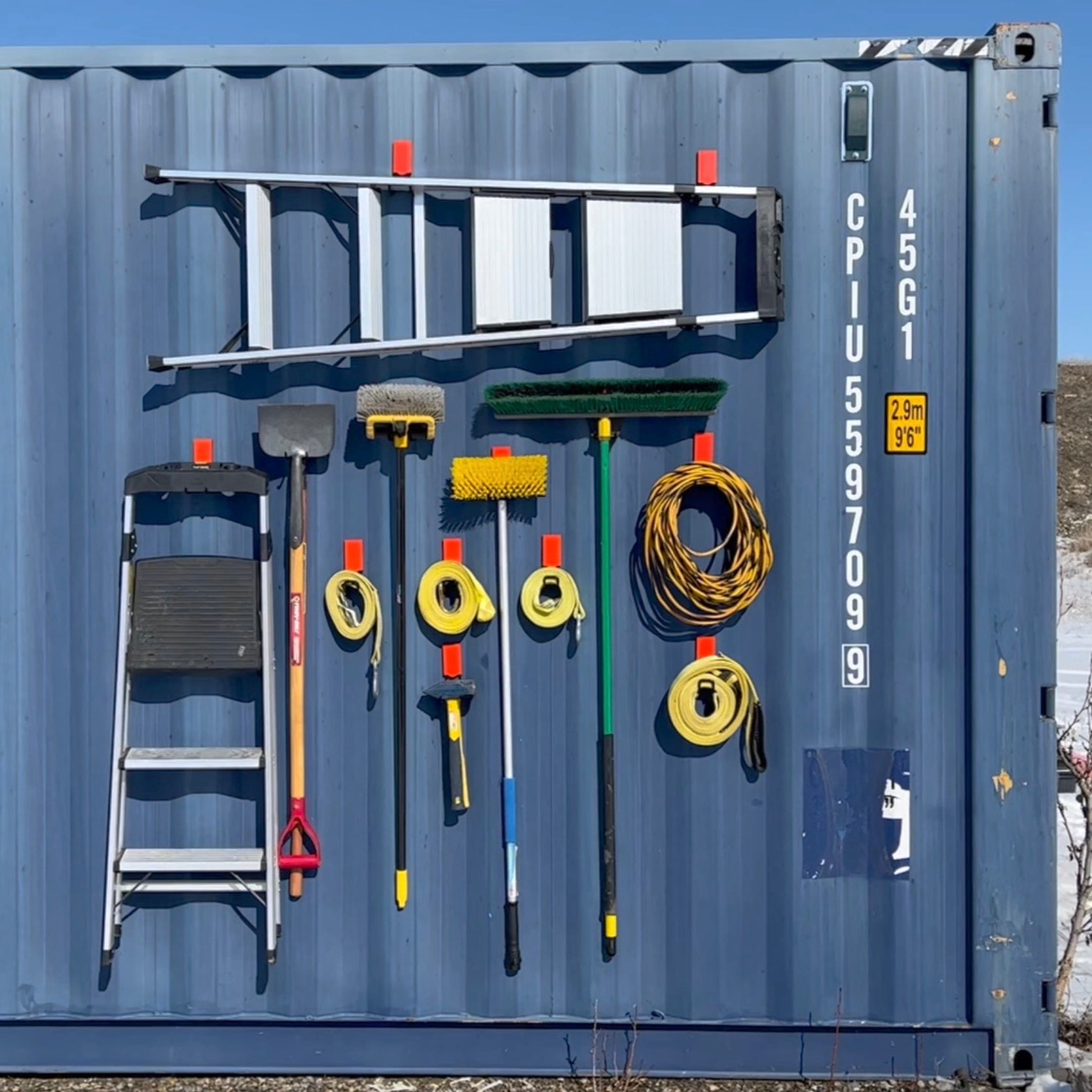 Heavy-duty Gator Magnetics 4.5 inch closed magnetic hook holding ladder, shovel, broom, extension cord, and cleaning tools on steel shipping container wall, industrial magnetic hook garage storage, tool organization, magnetic hook ladder holder, magnetic hook for outdoor storage, Gator Magnetics heavy-duty steel hook system.