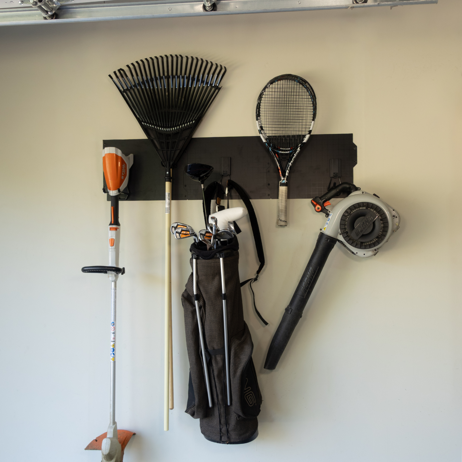 Black 50-inch magnetic wall storage system holding rakes, bags and a leaf blower.