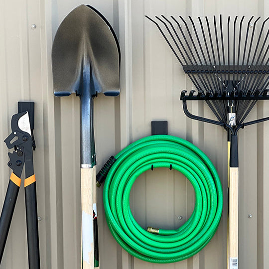 Black Gator magnetic hooks organize loppers, shovel, garden hose and rake on a steel wall.