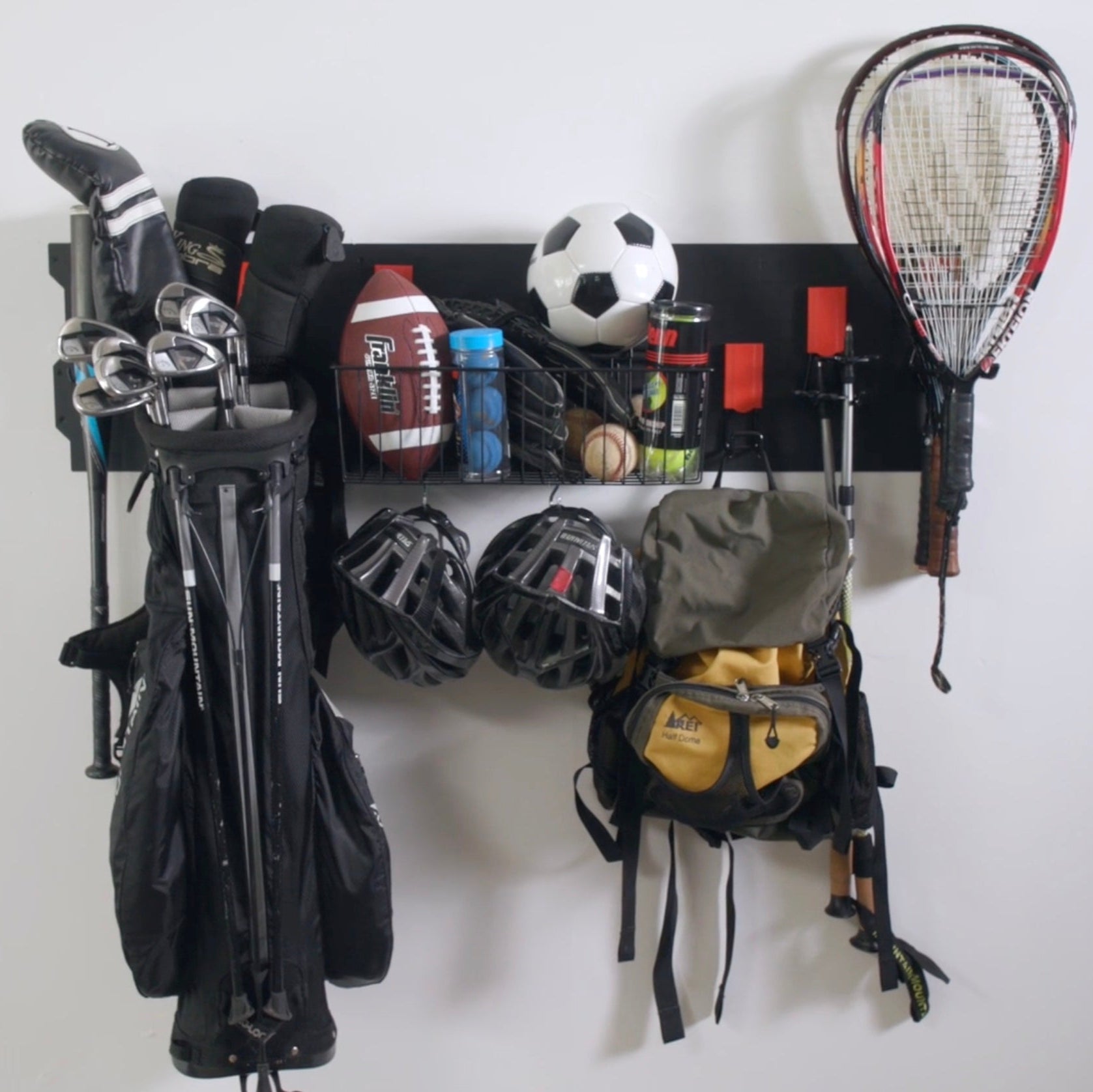 Black Gator Steel Wall Panel with red hooks holding golf clubs, a baseball bat and bicycle helmets.
