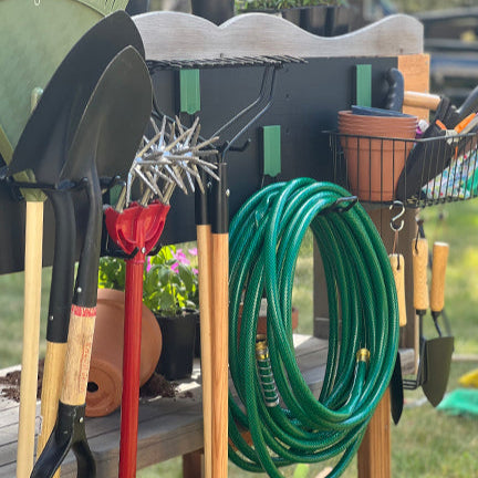 Green Gator magnetic hooks hold garden tools on a black Gator Steel Wall Panel.