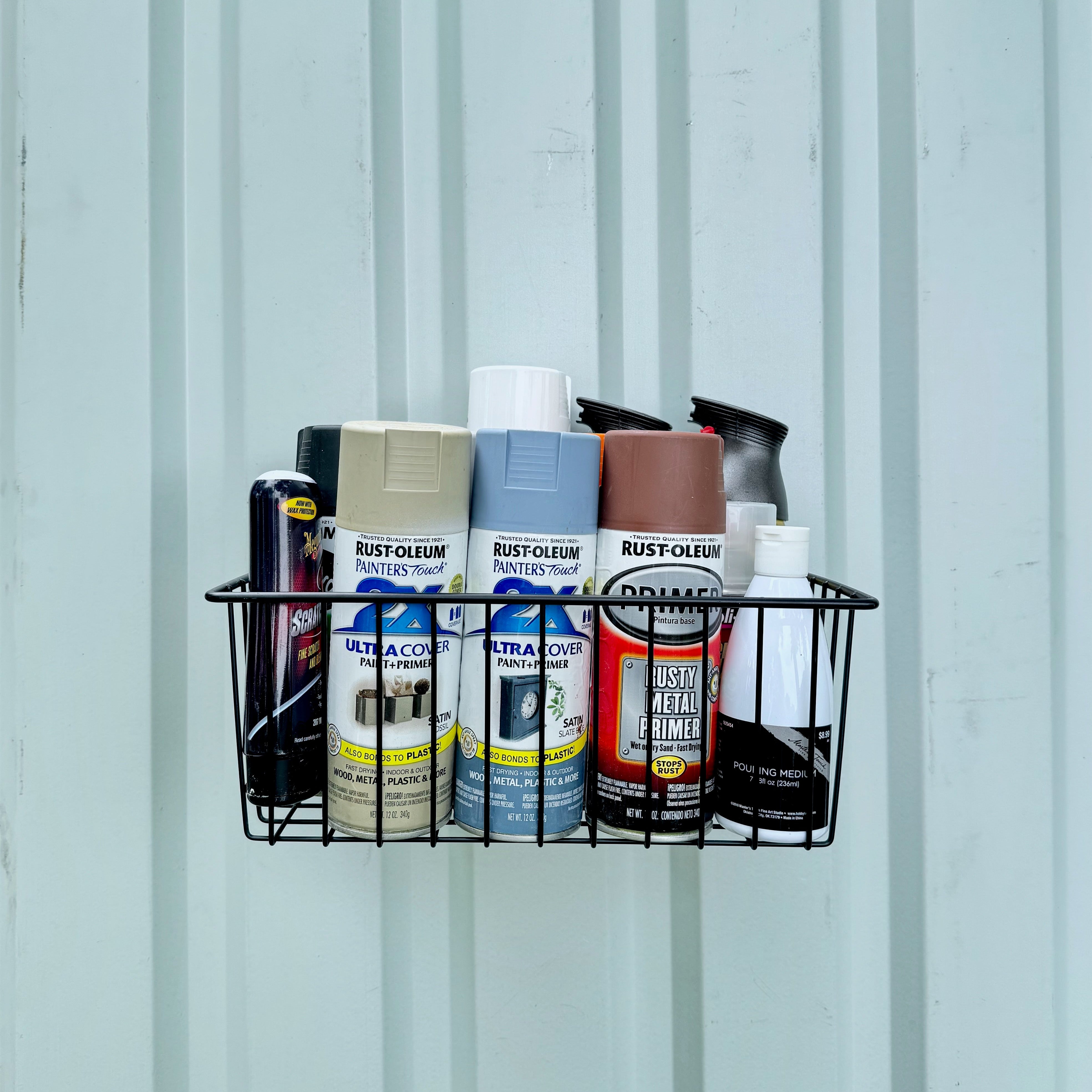 Gator Magnetics heavy-duty magnetic basket mounted on a corrugated steel wall in a pole barn or steel shed, providing convenient storage and organization for spray paint cans, primer, and cleaning supplies, keeping tools and materials within easy reach.