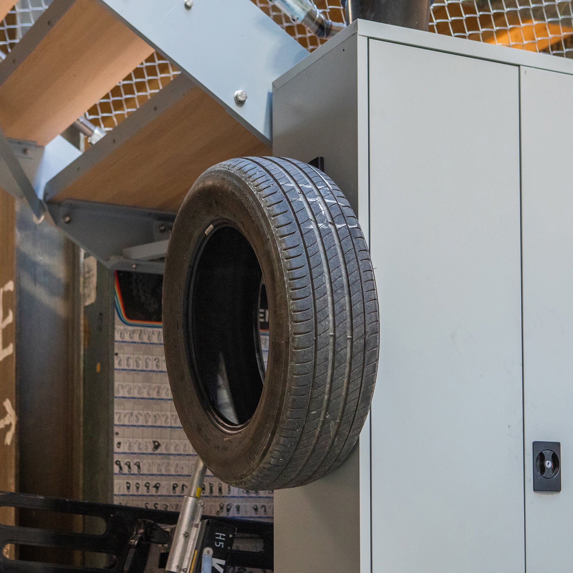 Gator Magnetics magnetic hook holding spare car tire on metal cabinet, 4.5-inch closed hook for automotive storage, garage organization, and workshop equipment hanging.