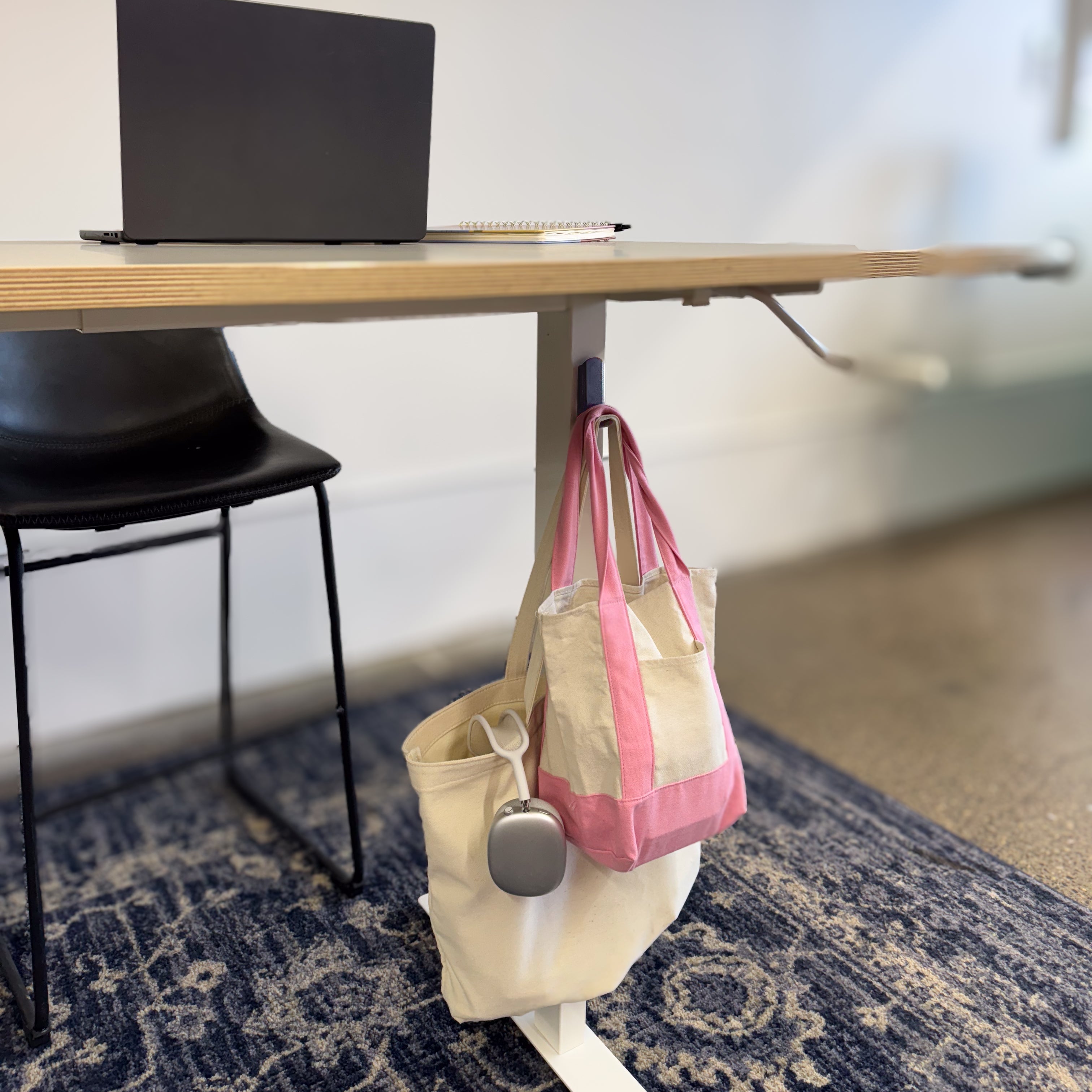 Gator magnetic hook holds two canvas tote bags on the steel leg of an office desk.