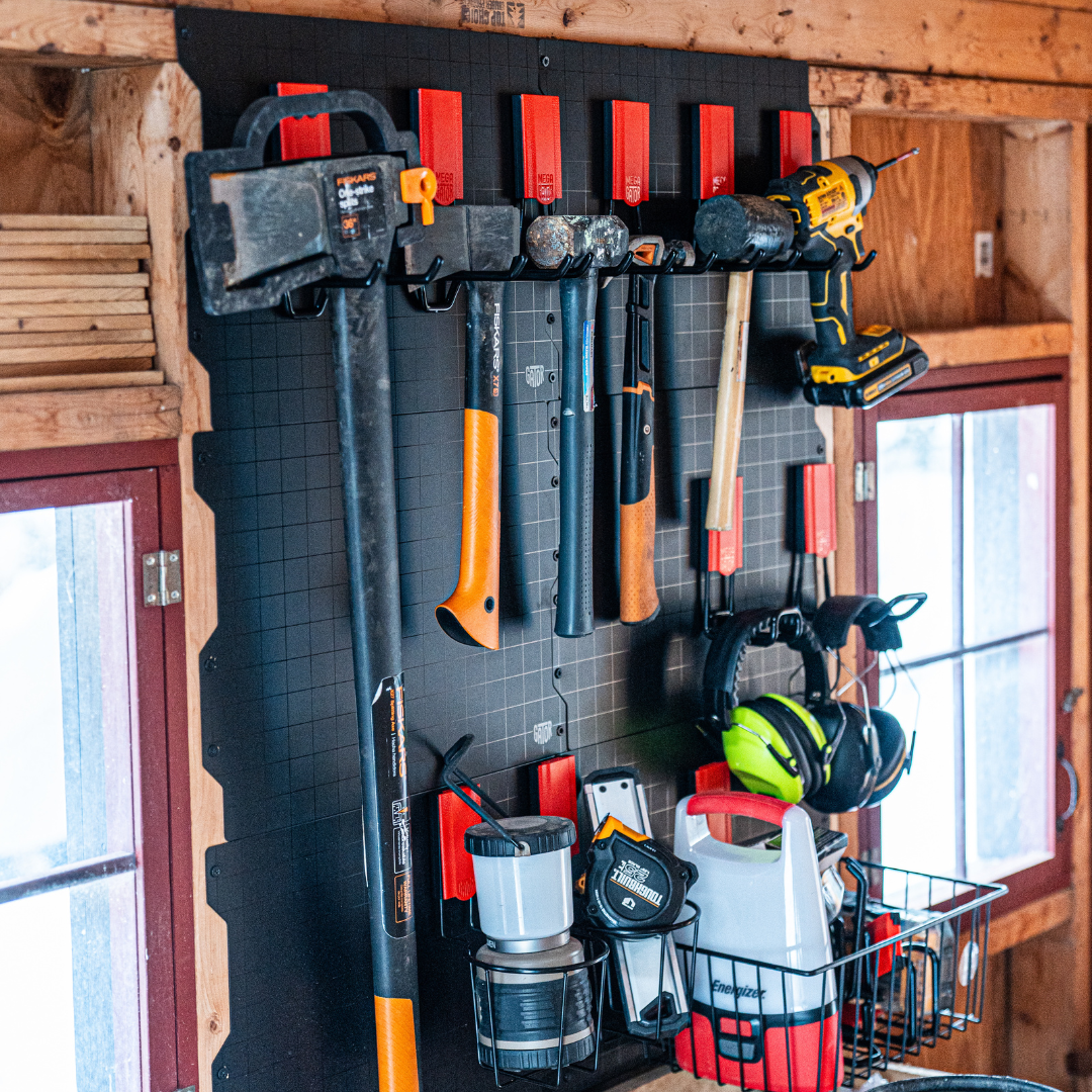 Gator Steel Wall Panel with red magnetic hooks organizing axes, hammers, drill, lantern and hearing protection.
