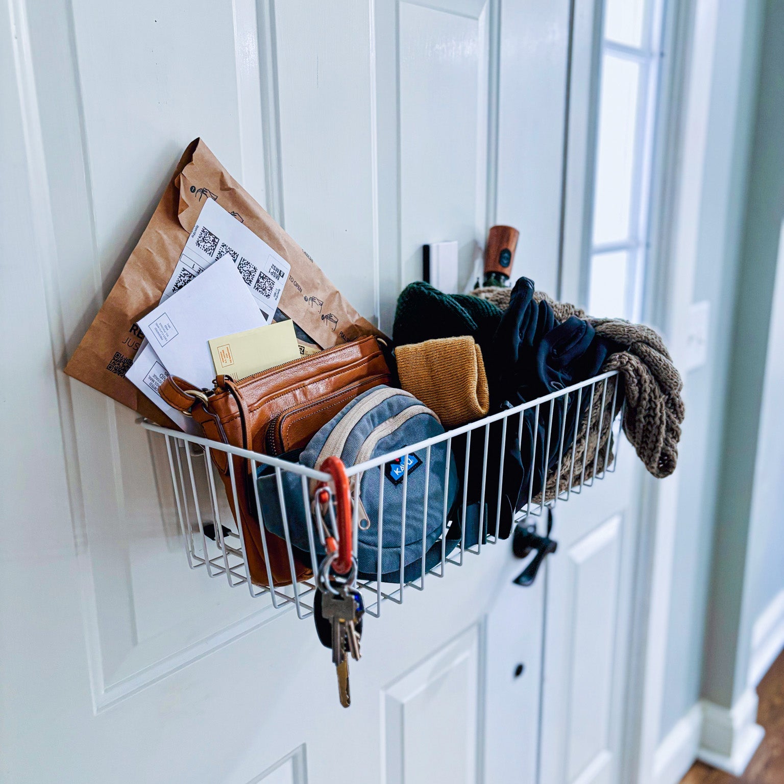 White Gator magnetic storage basket on a steel door holding a clutch, small pouch and mail.