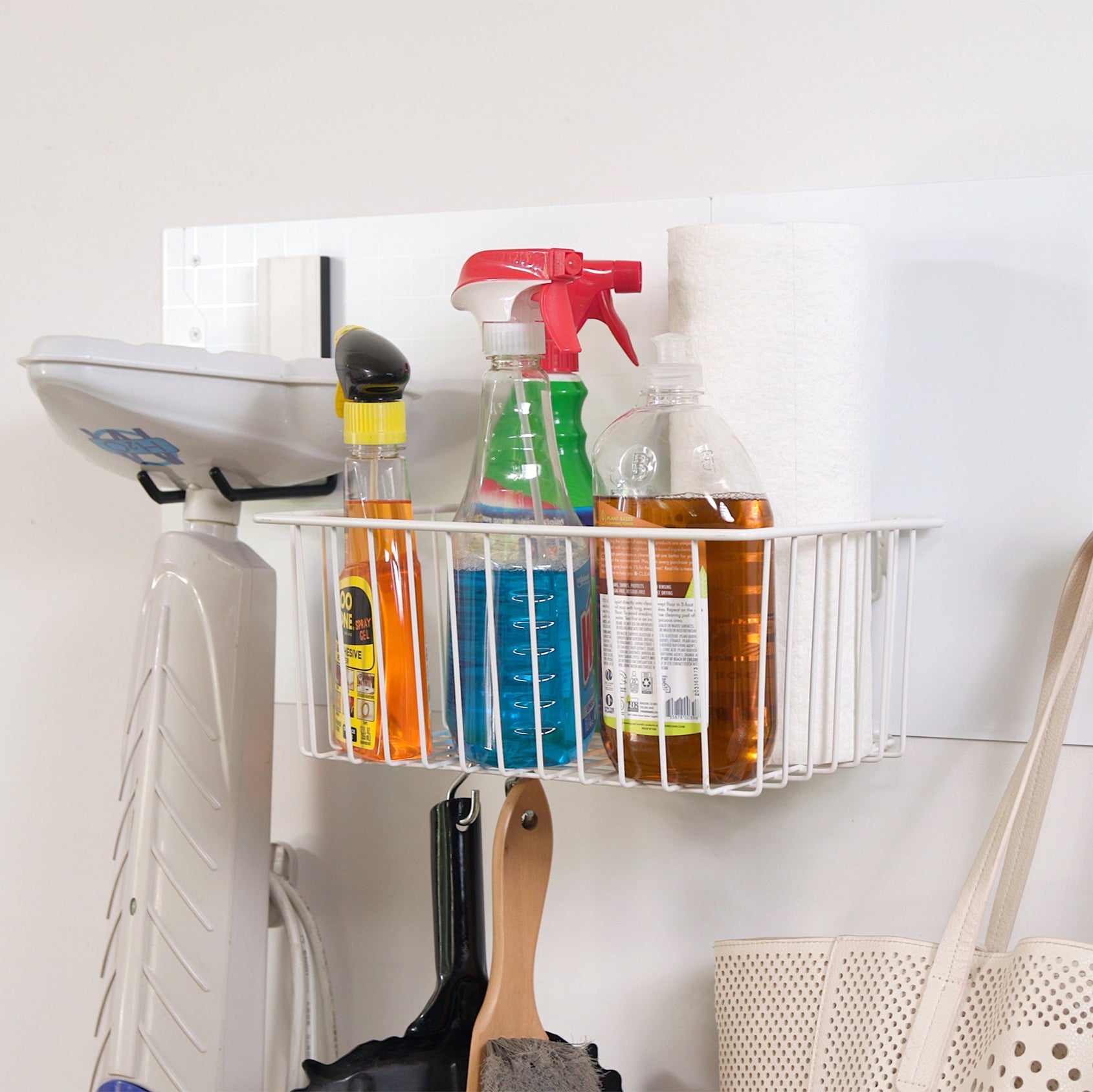 White Gator magnetic wire basket holds cleaning bottles and paper towels on a steel wall panel.
