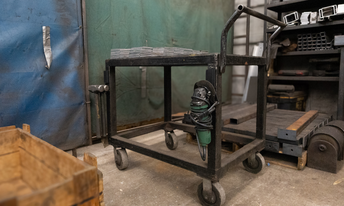 Green angle grinder hanging from a red Gator heavy-duty magnetic hook on a black steel shop cart.