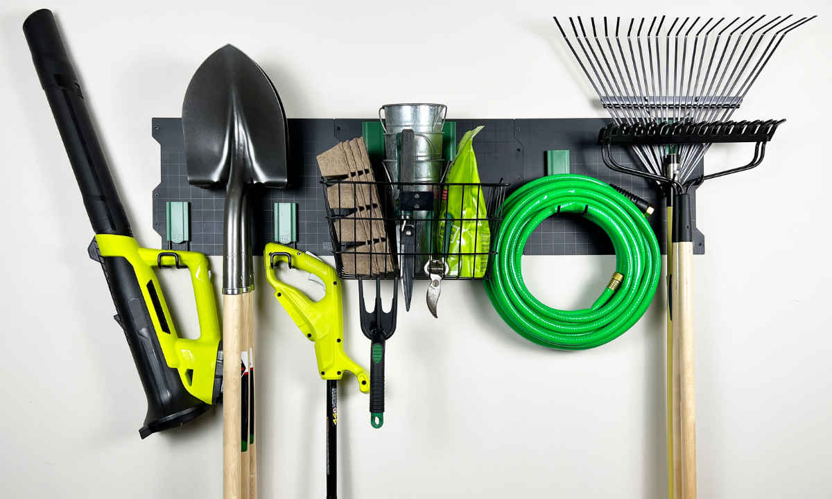White Gator Steel Wall Panel with magnetic hooks and basket organizing yard tools and garden hose.