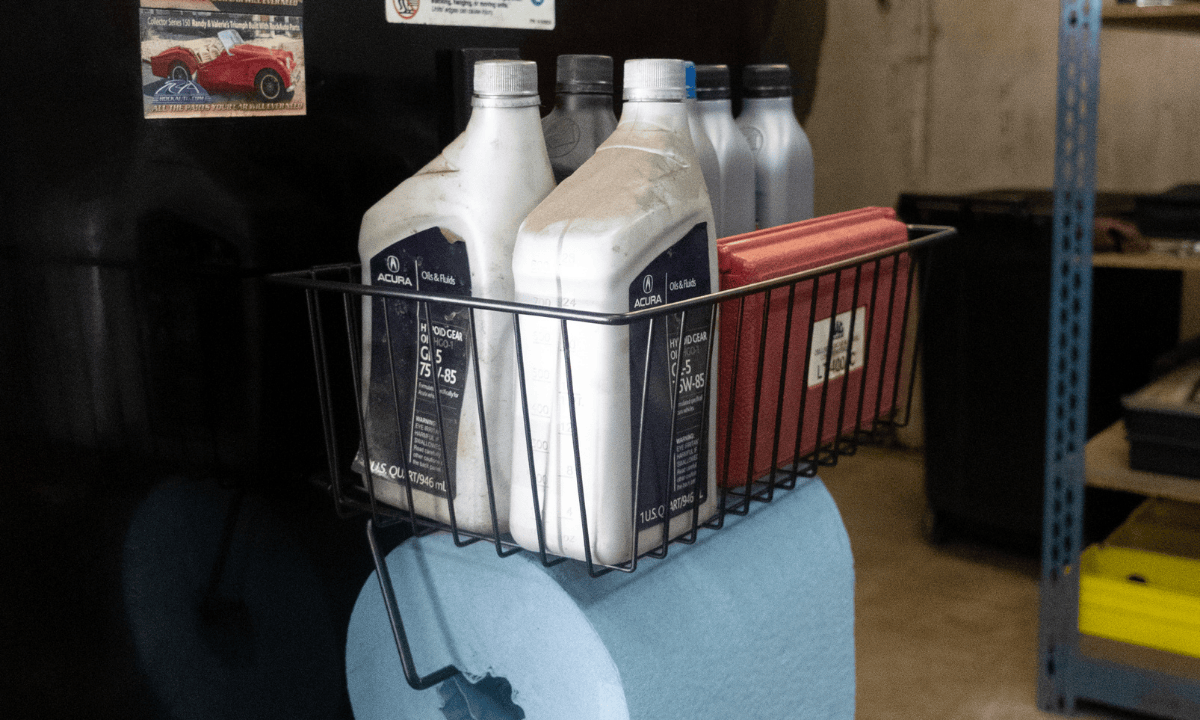 Black Gator magnetic basket holding motor oil containers on steel workshop equipment.