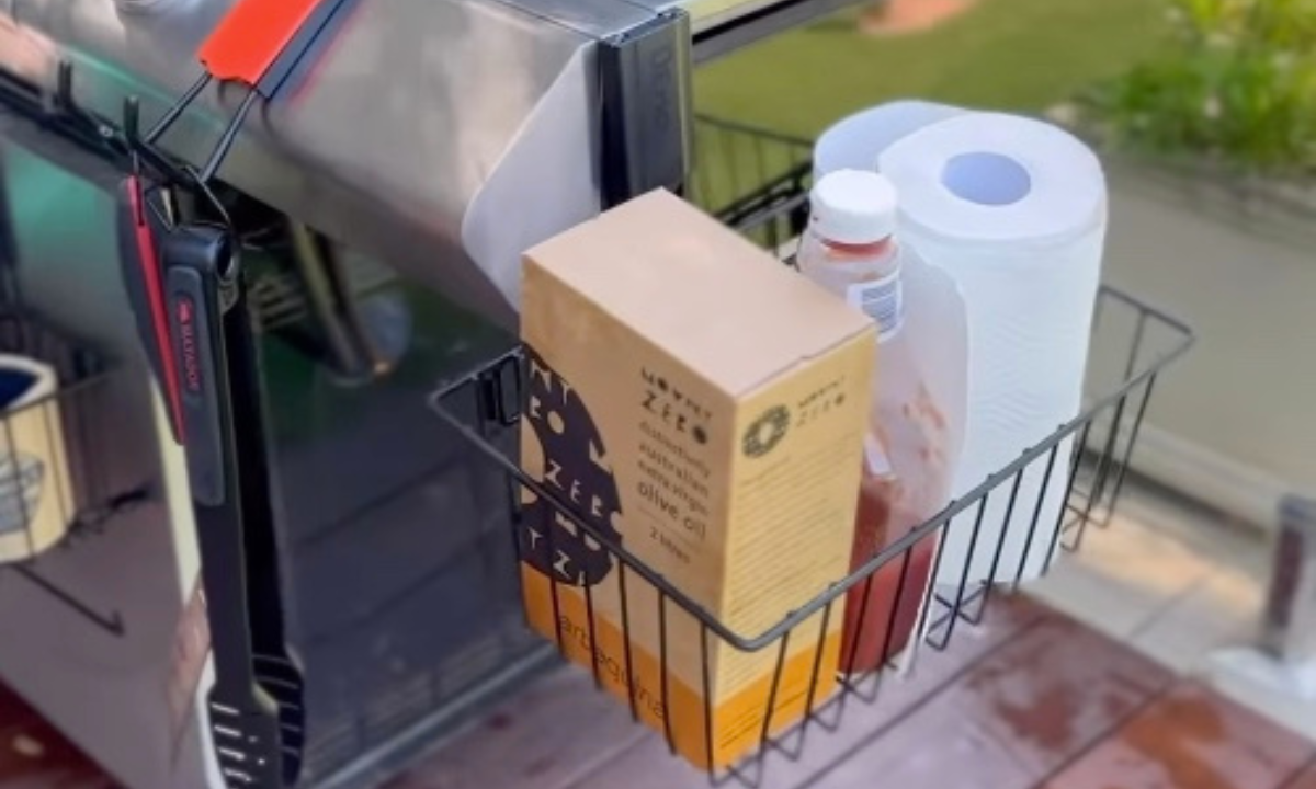 Gator magnetic storage basket on a stainless steel grill holding olive oil, ketchup and paper towels.