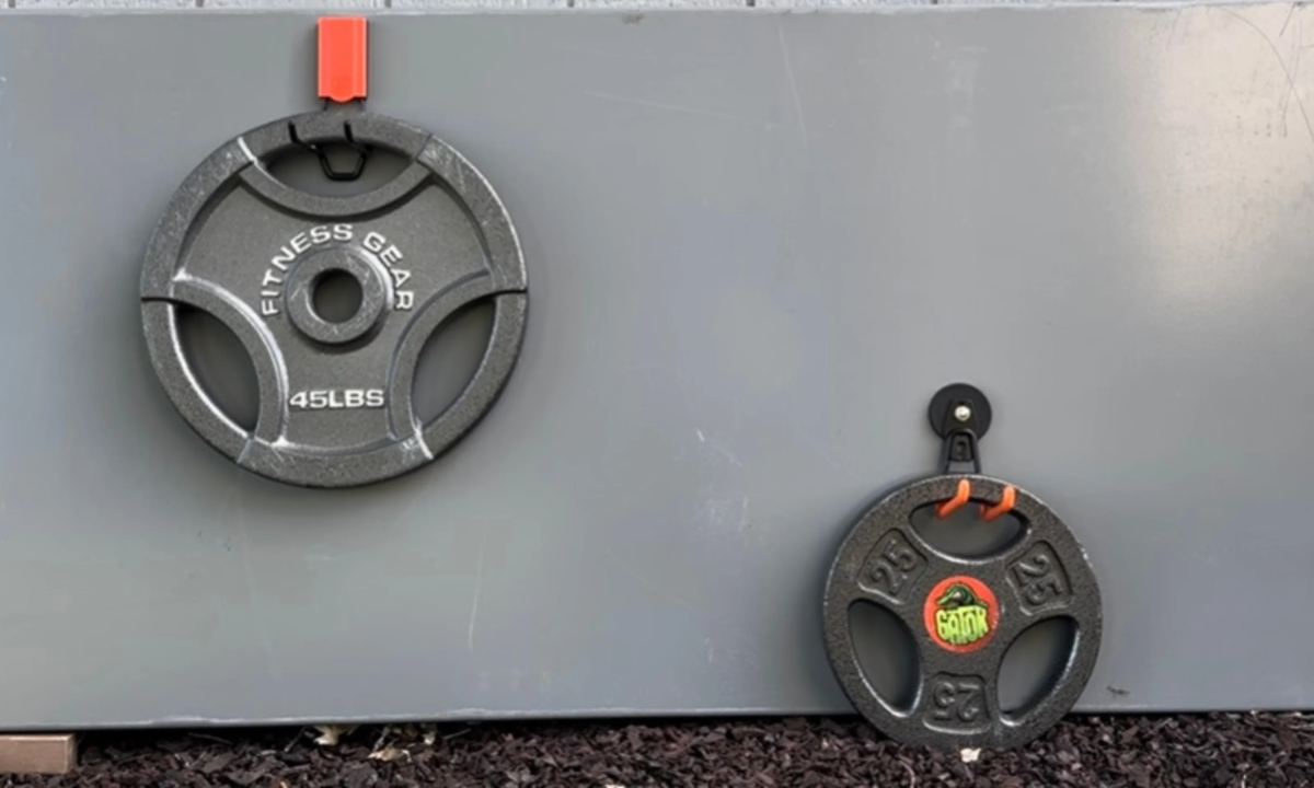 Red Gator magnetic hooks hold 45- and 25-pound weight plates on a gray steel wall panel.