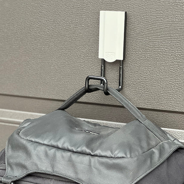 White 2.5" closed magnetic hook holding a backpack, with a 25 lbs capacity. This hook is perfect for organizing backpacks, tools, and other items in home garages, workshops, or professional environments. Provides strong, reliable magnetic attachment for efficient storage.