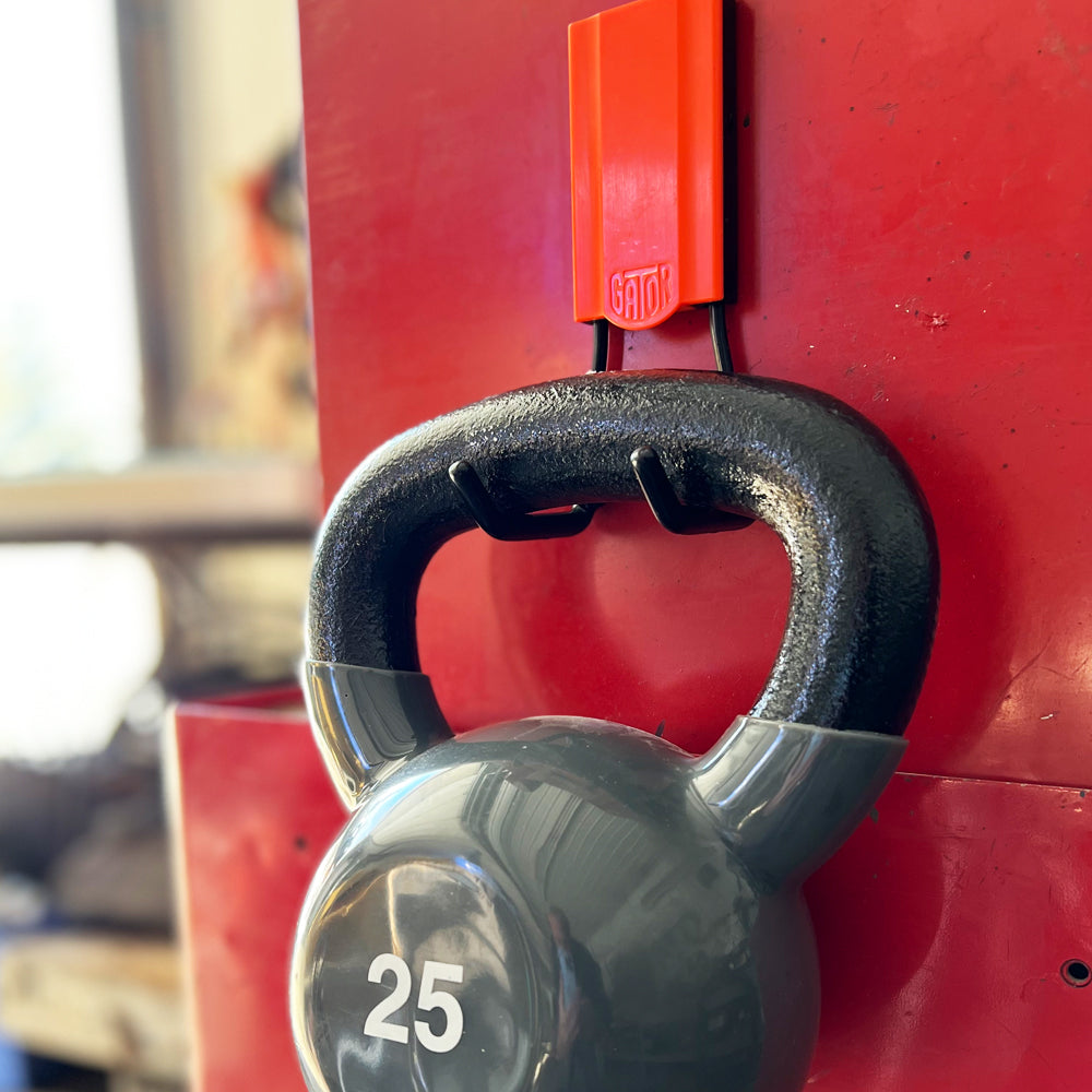 A robust red 4-inch open magnetic hook securely holding a 25 lbs weight. Designed for heavy-duty storage in garages, workshops, and industrial settings, this hook demonstrates its superior magnetic strength, offering reliable support for large, heavy items, ensuring an organized and safe workspace.