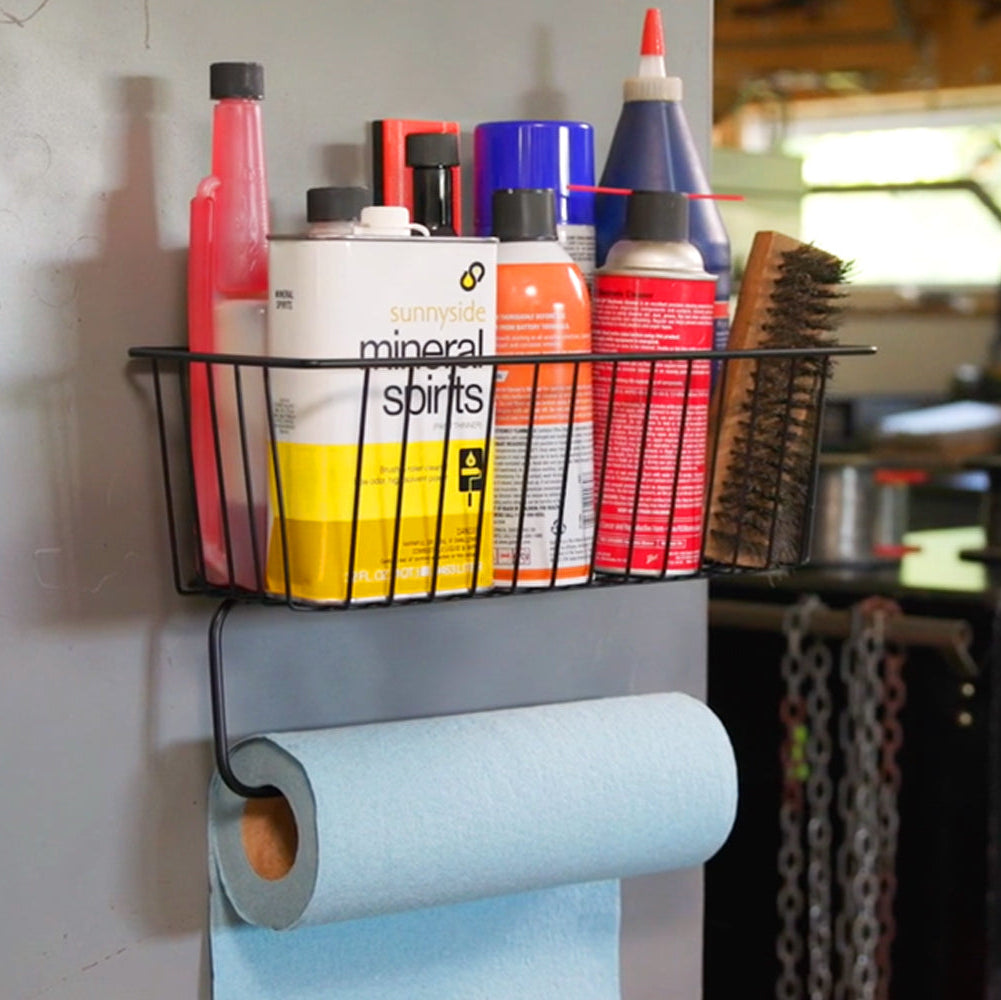The towel basket is shown holding various garage supplies, with a paper towel holder attached to the bar. This image demonstrates the basket’s versatility and organizational capabilities, featuring both functional storage and convenient paper towel access.