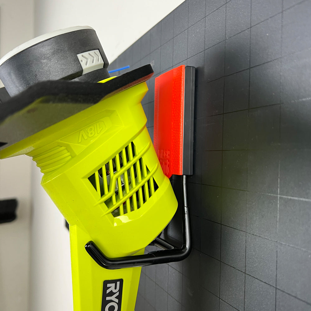 A bold red 3-inch open magnetic hook holding a Ryobi weed wacker. This heavy-duty hook is ideal for organizing power tools in busy workspaces like garages and workshops. With its strong magnetic hold, it provides a secure and practical storage solution for heavy tools, keeping them within easy reach while freeing up valuable space.