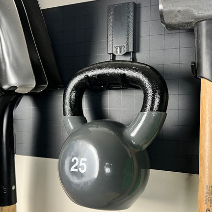 A 25-pound kettlebell hangs from a Gator magnetic hook on a black Gator Steel Wall Panel.