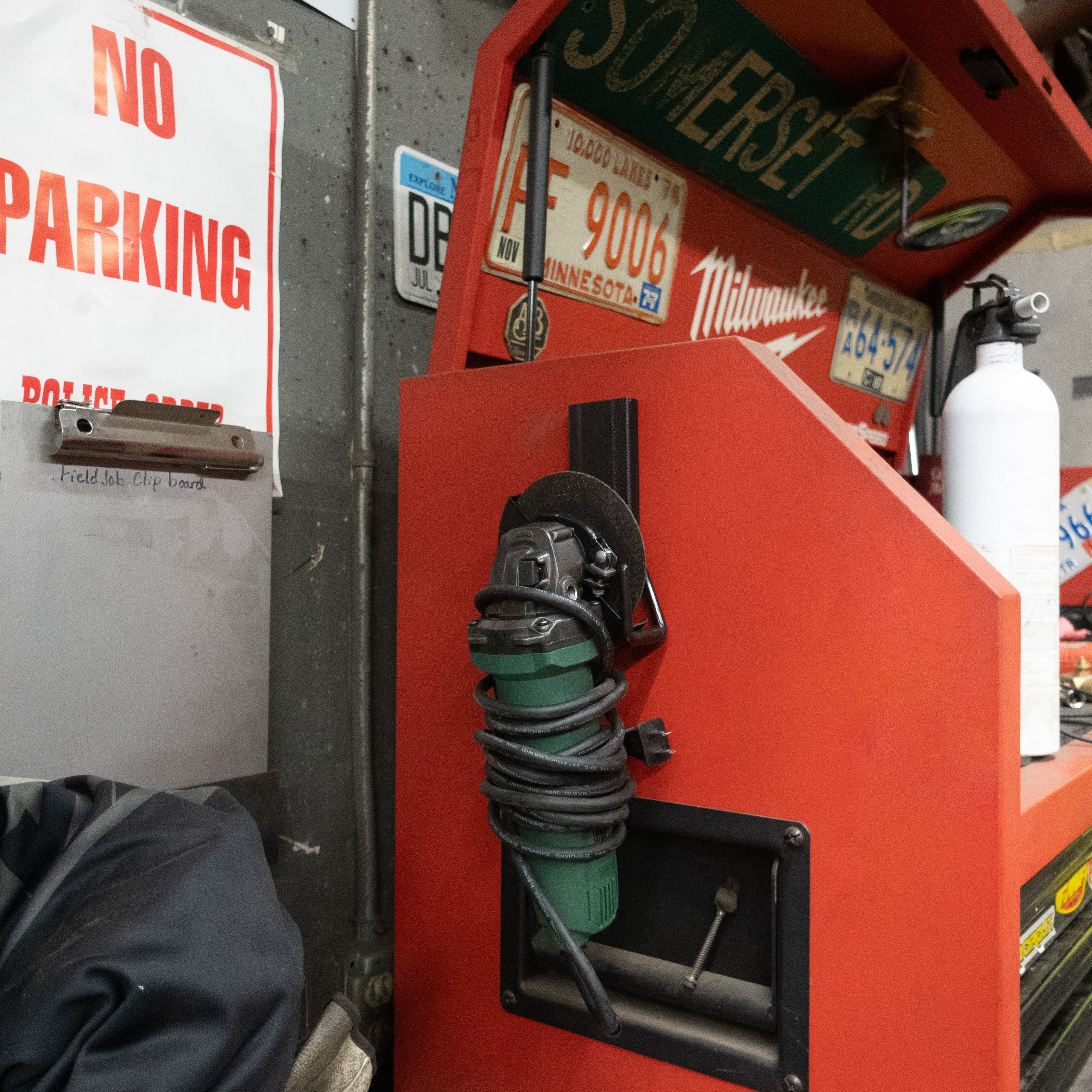 Angle grinder hanging from a red Gator magnetic hook on the steel side of a red toolbox.