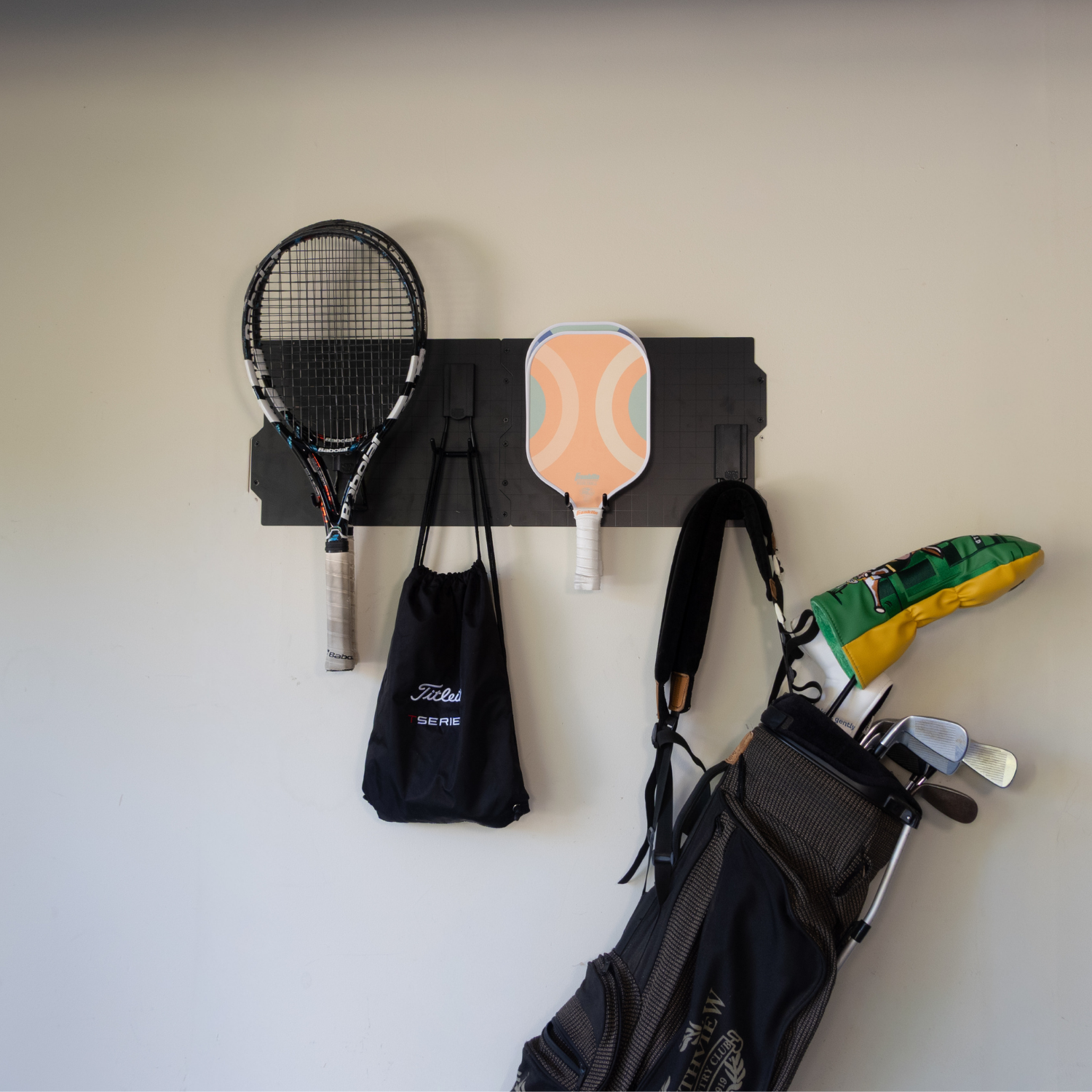 Black 34-inch magnetic wall storage system holding rackets, bags, bats and sports gear.