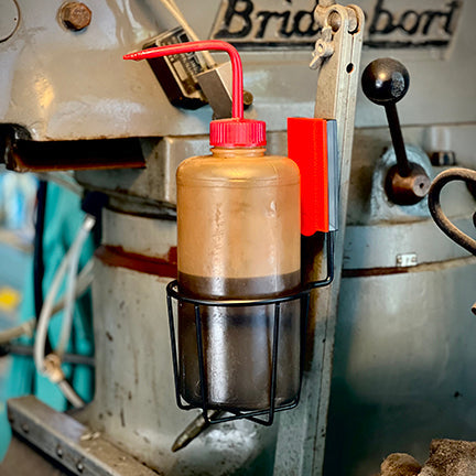 A black Gator Magnetics magnetic cup holder holds a brown oil bottle on a gray steel machine.