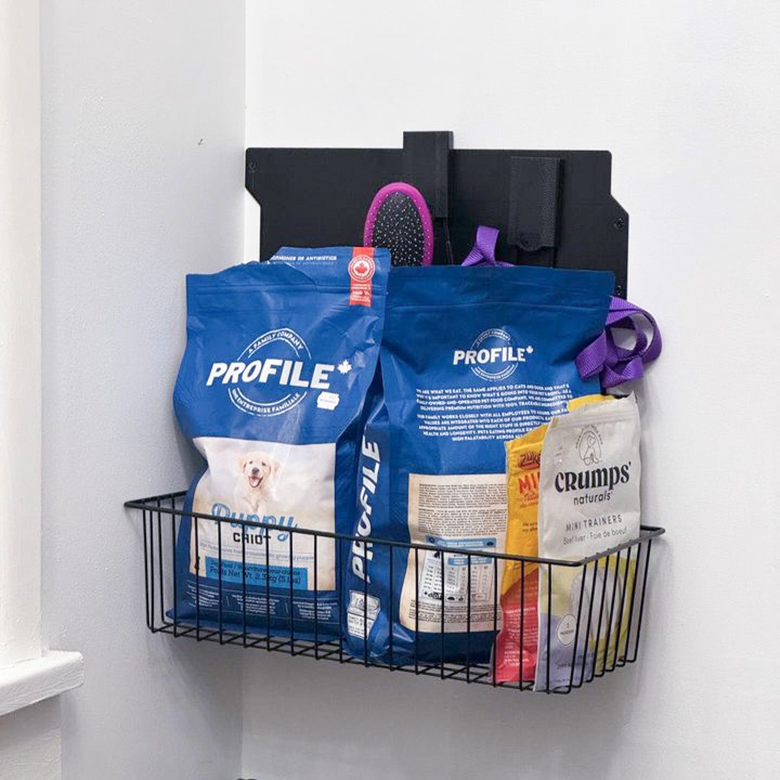 Black Gator magnetic storage basket on a steel wall panel holding dog food, treats and a pet brush.