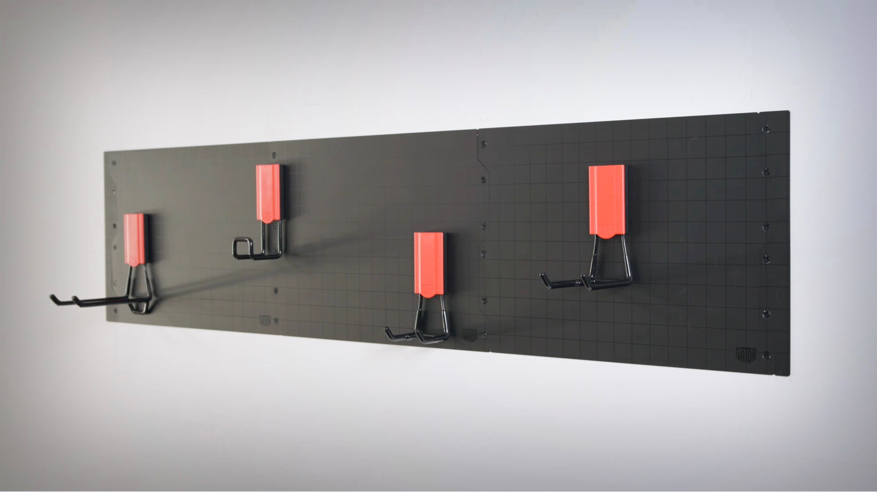 Four red and black Gator Magnetics magnetic hooks are mounted on black Gator steel wall panels attached to a steel wall.
