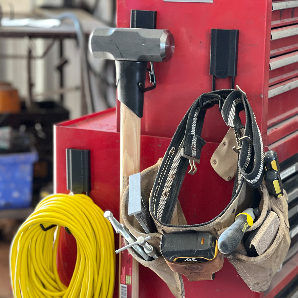 Hammer, extension cord and loaded tool belt hang from red Gator magnetic hooks on a steel toolbox.