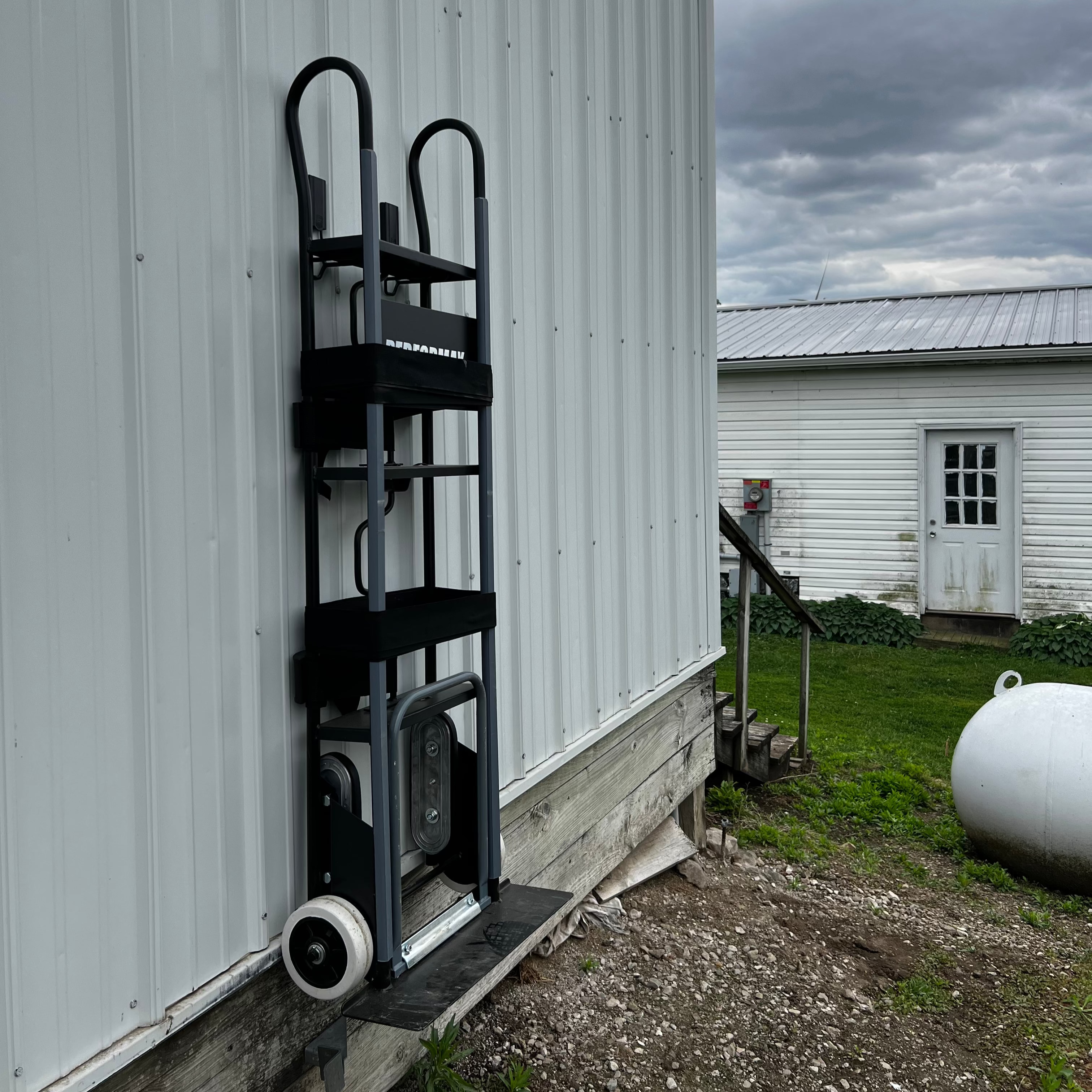 Hand truck hanging from a Gator magnetic hook on a corrugated steel exterior wall.