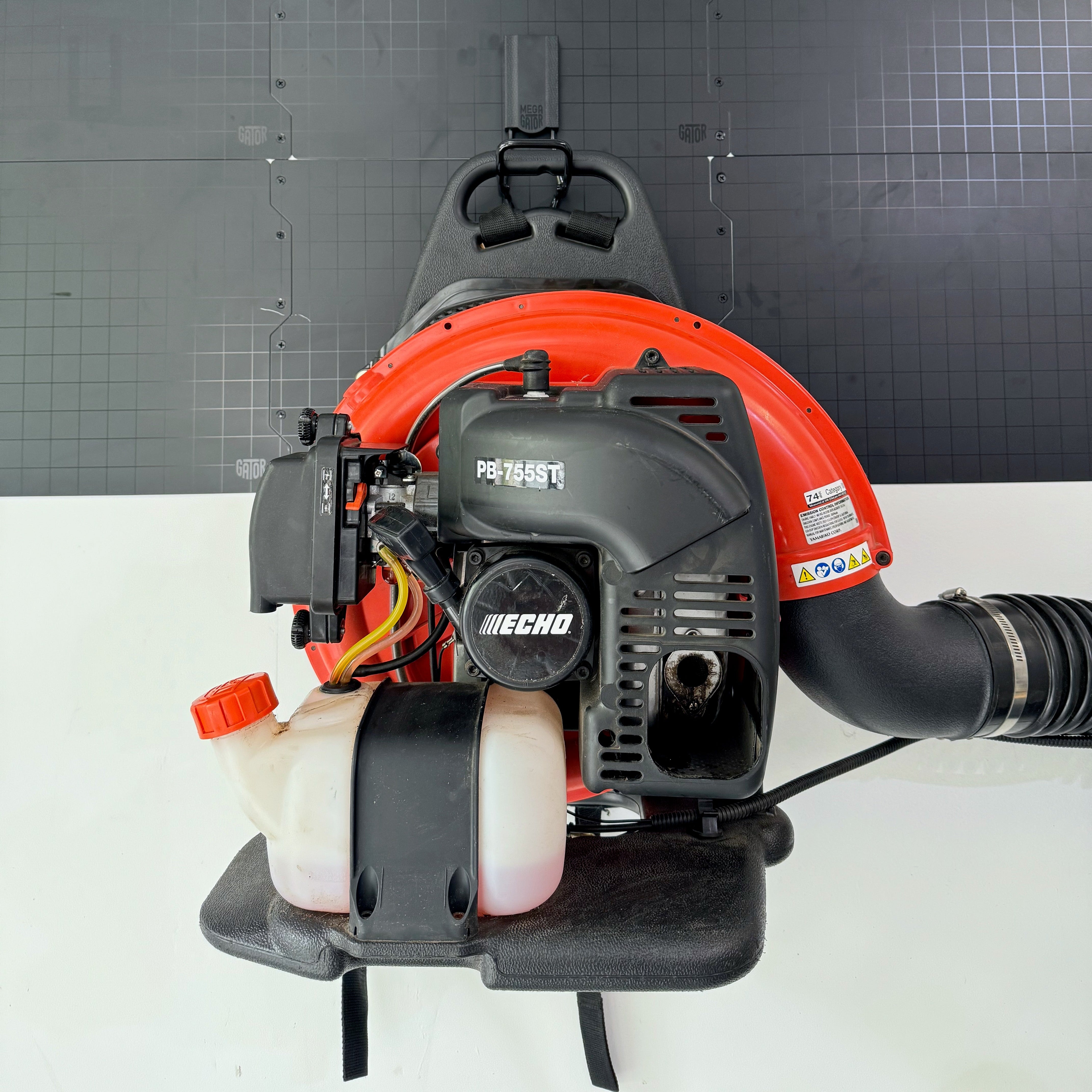 Leaf blower hanging from a Gator magnetic hook on a black steel wall panel.