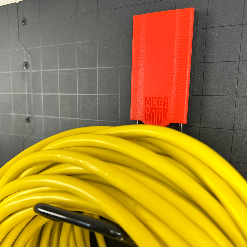 A red Gator Magnetics magnetic hook secures a large yellow extension cord on a black steel toolbox panel.