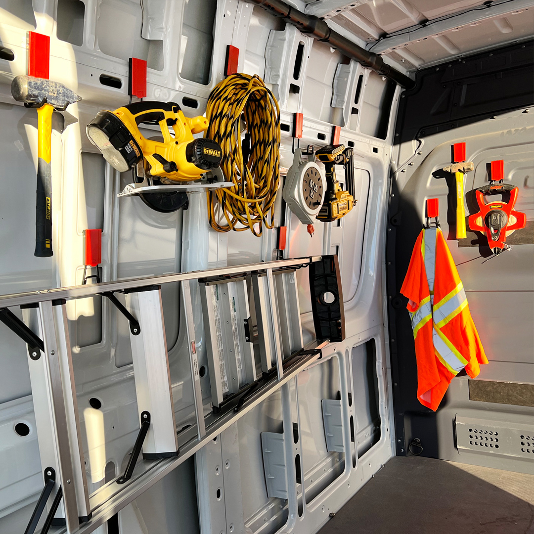 Red Gator magnetic hooks organize a hammer, drill, cord, level, safety vest and ladder inside a steel van.