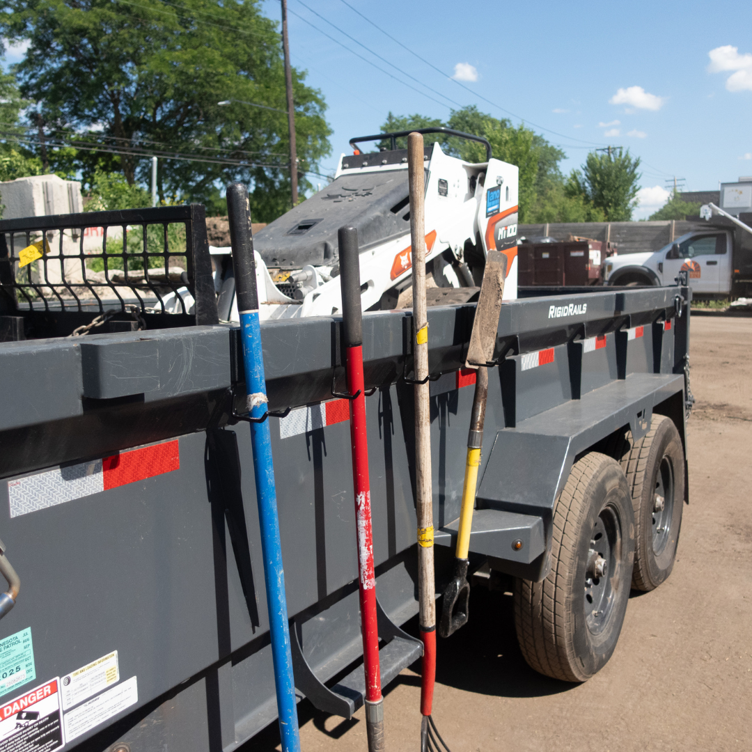 Red Gator magnetic hooks hang a garden fork, rake, shovel and hoe on a steel utility trailer.