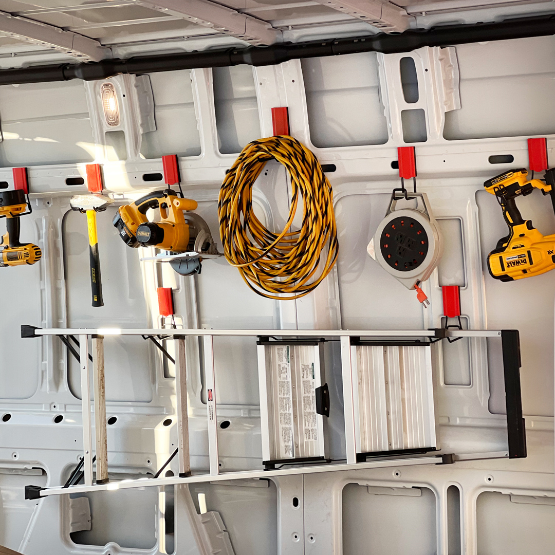 Red Gator magnetic hooks organize a ladder, extension cord, hammer and drills inside a steel van.