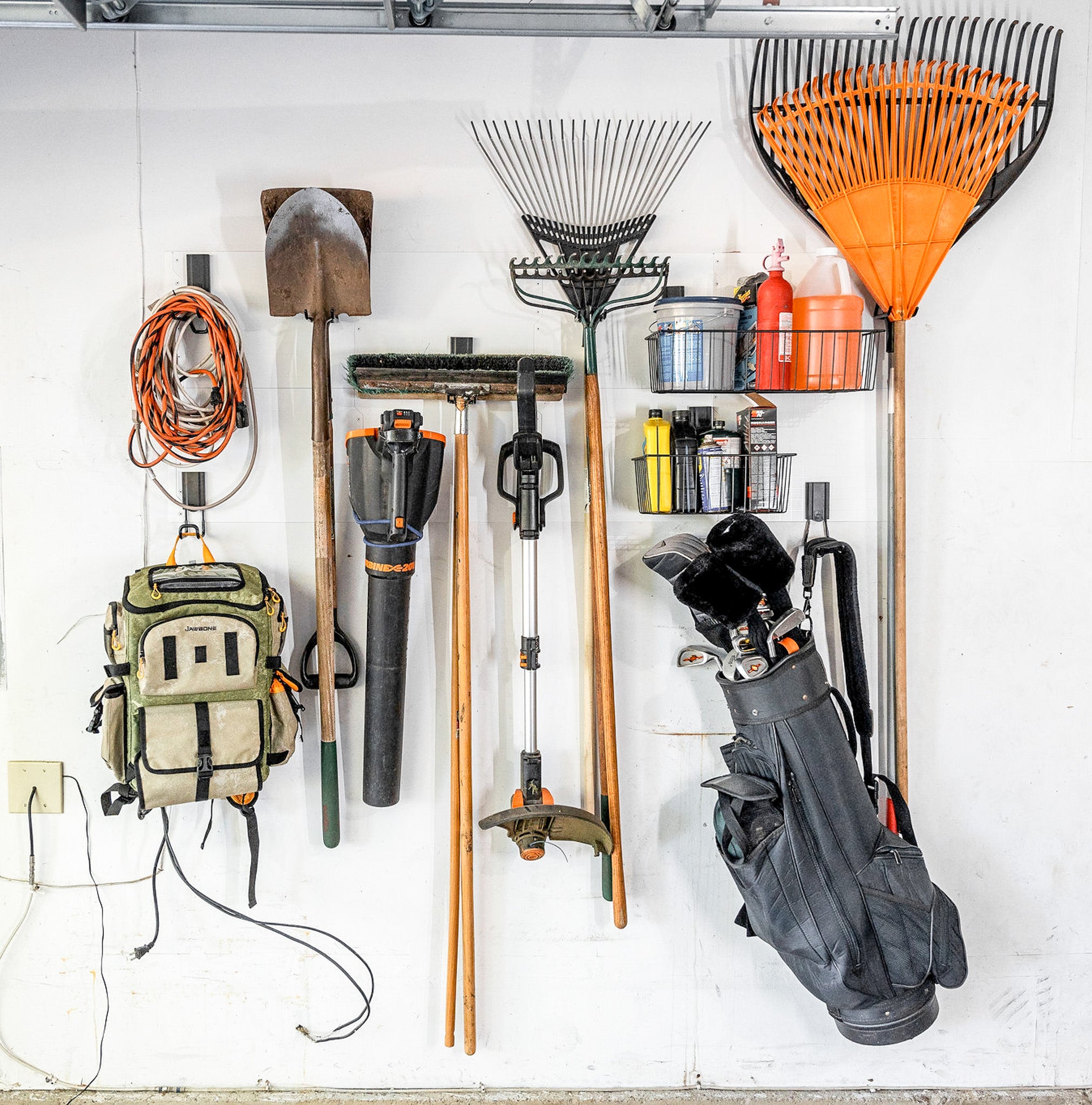 Shovels, rakes, trimmer, leaf blower and extension cord organized on a white Gator Steel Wall Panel.