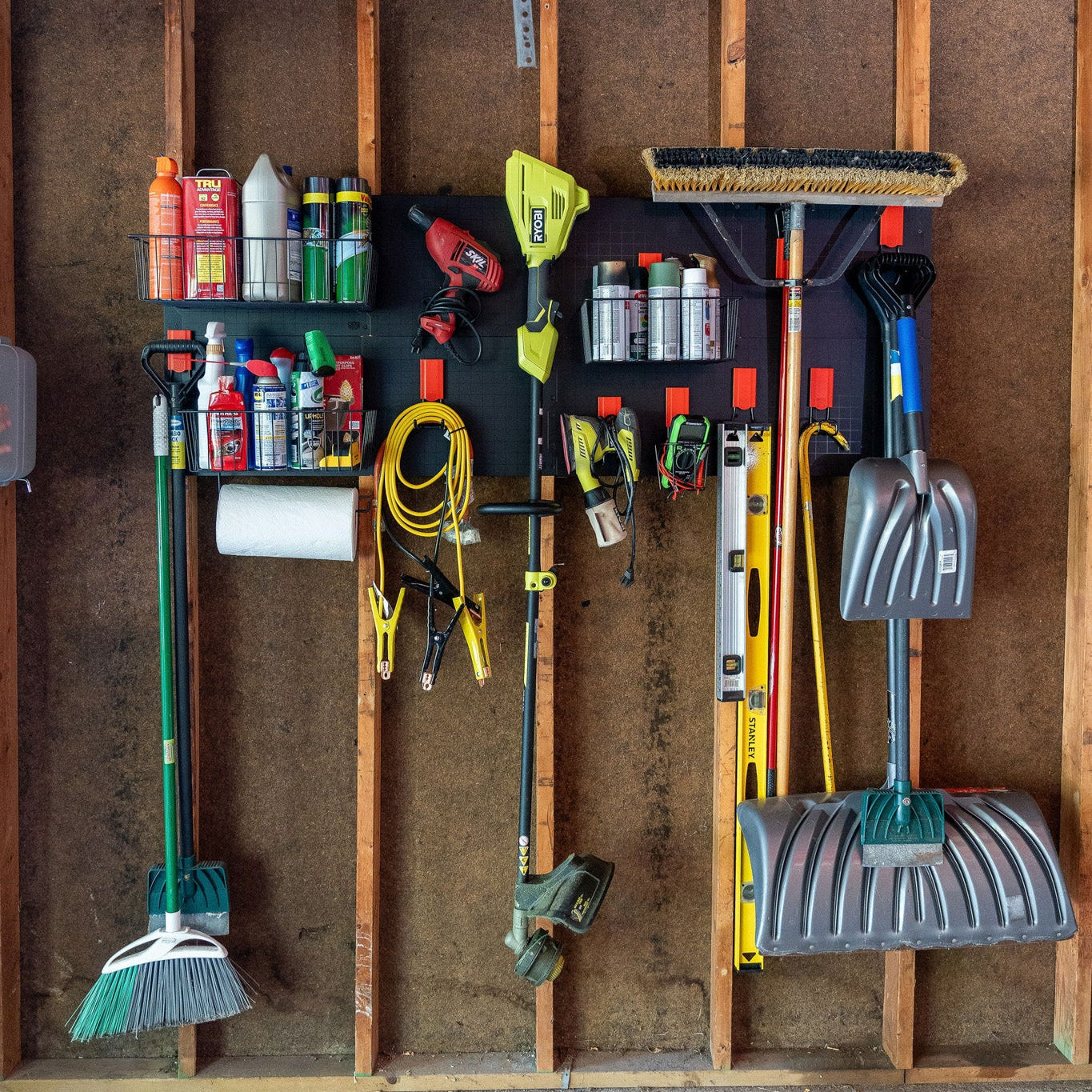 Gator Steel Wall Panels mounted between garage studs with magnetic baskets holding spray cans and fluids.