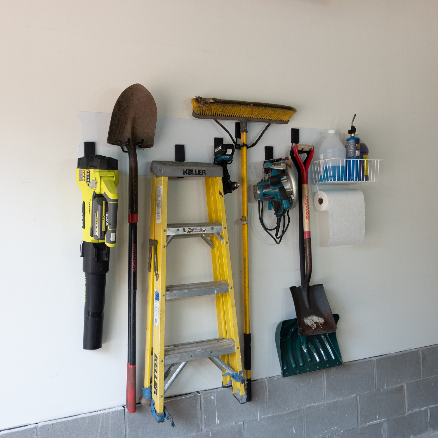 White 67-inch magnetic wall storage system organizing a ladder, shovel, blower and basket.