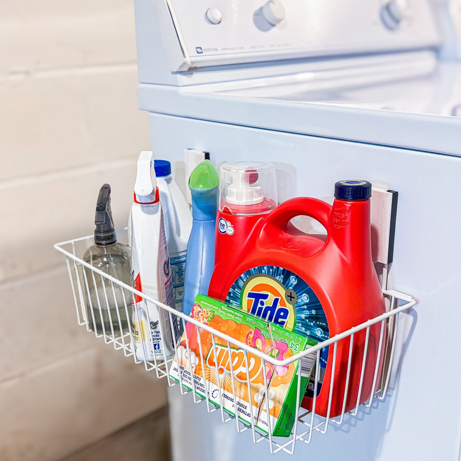 White Gator large magnetic basket on a washing machine holding laundry detergent and fabric softener.