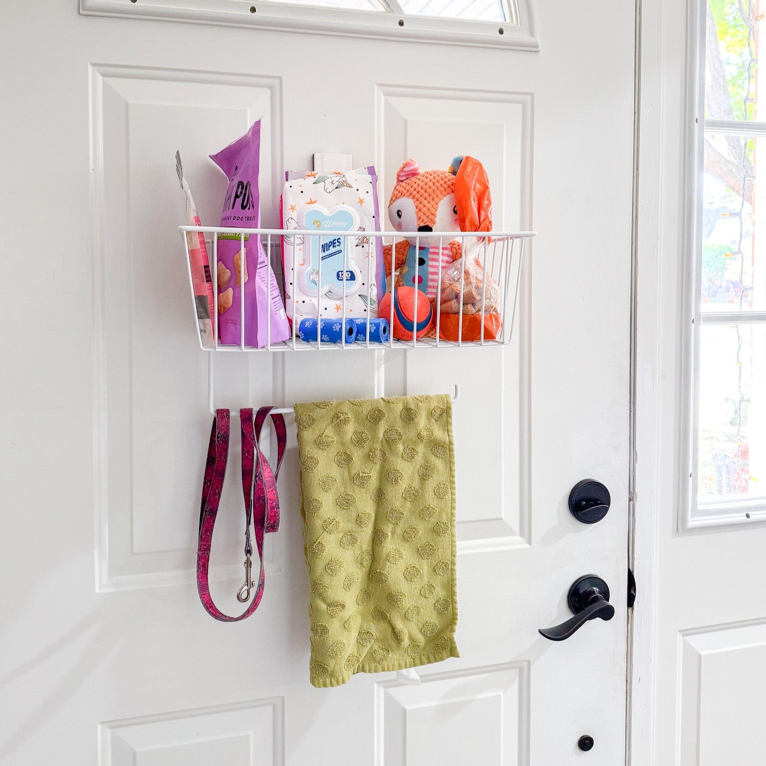 White Gator magnetic basket on a steel door holding dog treats, wipes, plush toy and ball.