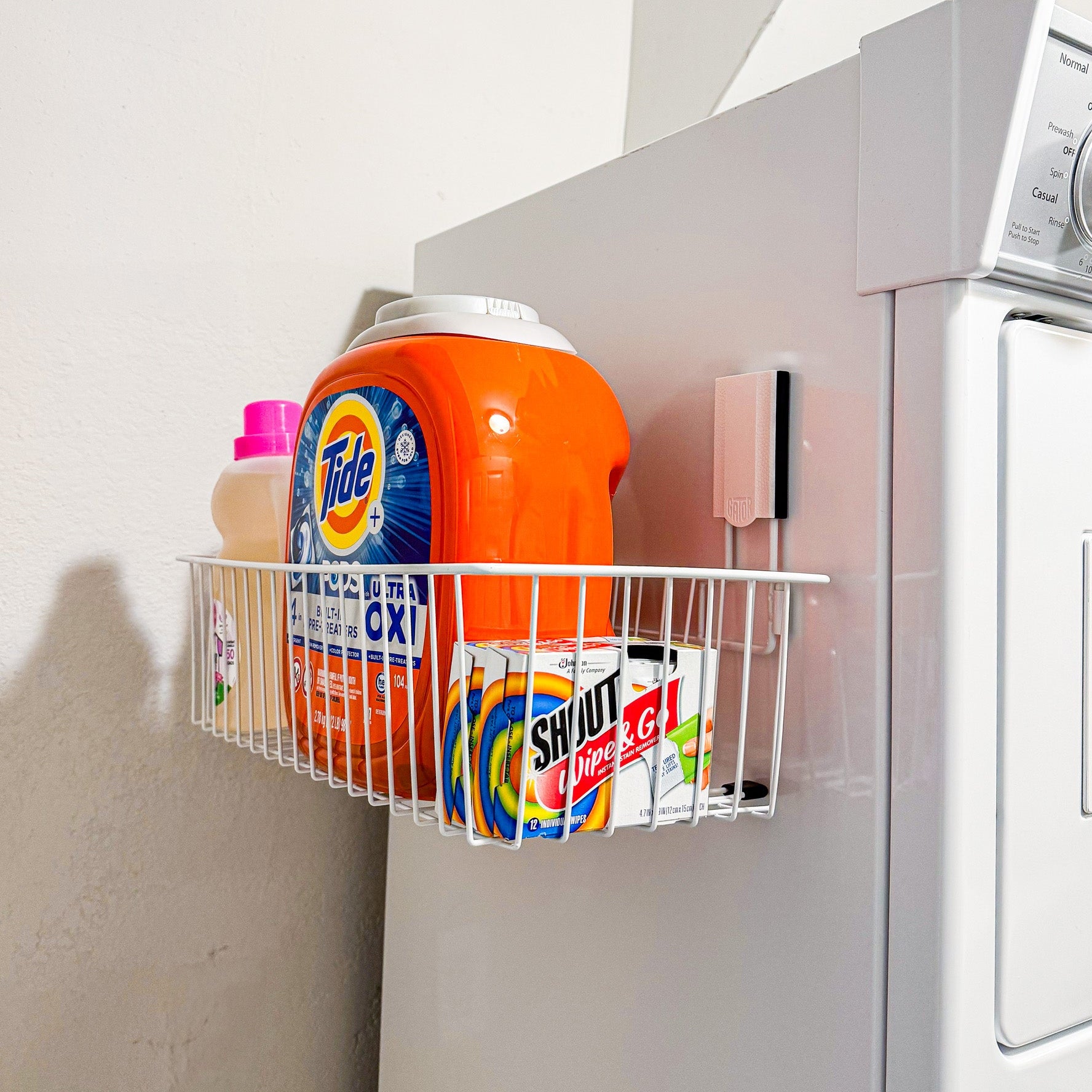 White Gator magnetic basket on a washing machine holding laundry detergent and fabric softener.