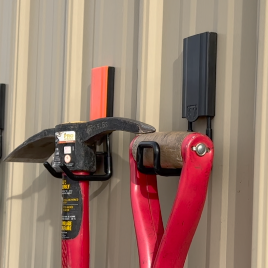 Pickaxe and red-handled tool mounted on a vertical metal wall using Gator Magnetics magnetic storage hooks